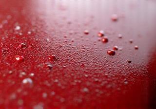 Extreme close-up of car paint surface showing microscopic imperfections - illustrates the vulnerability of paint